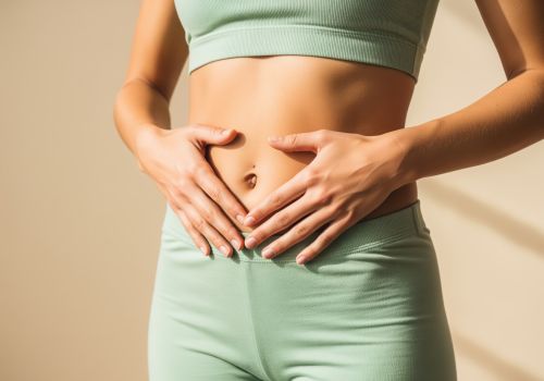 A woman wearing green athletic clothing holding her stomach.
